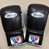 Winning black silver boxing gloves on gym canvas top view