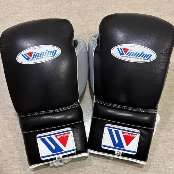 Winning black silver boxing gloves on gym canvas top view